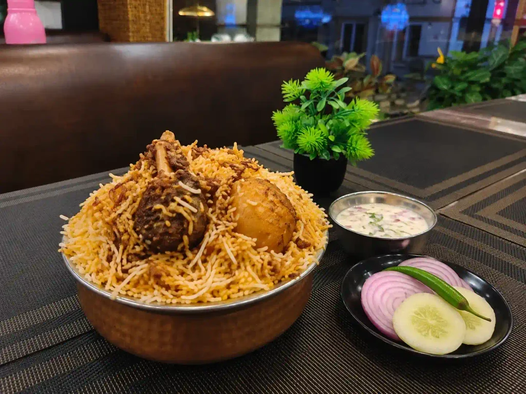 Kolkata mutton biryani served at table with salad and raita