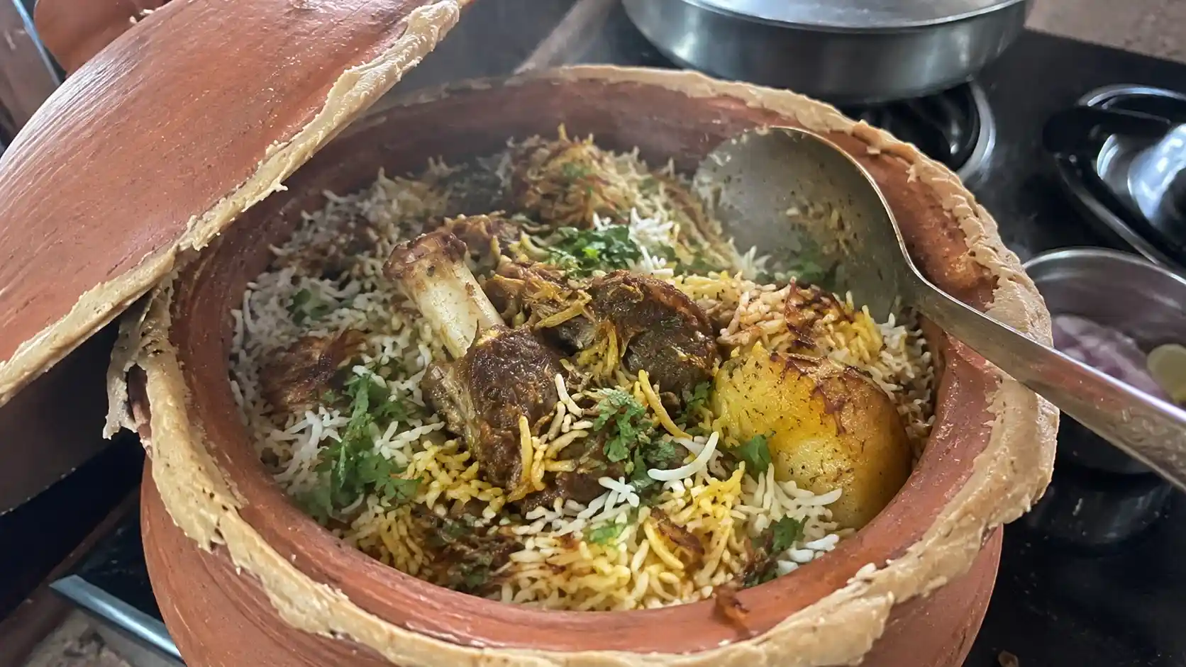 Kolkata mutton biryani served from a handi showing rice, mutton and aloo