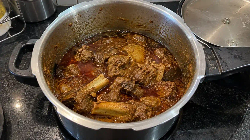 Cooked mutton with rogan (rendered fat) visible, ready for layering
